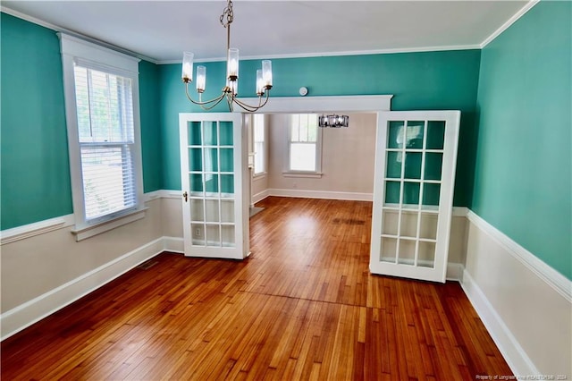 unfurnished dining area featuring hardwood / wood-style flooring, a healthy amount of sunlight, and a chandelier