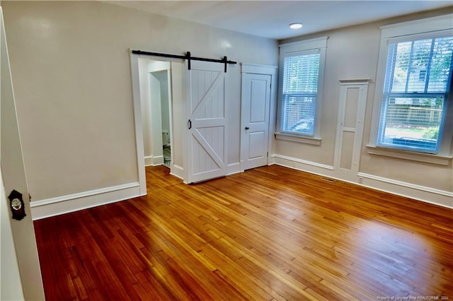 unfurnished bedroom featuring a barn door and wood-type flooring