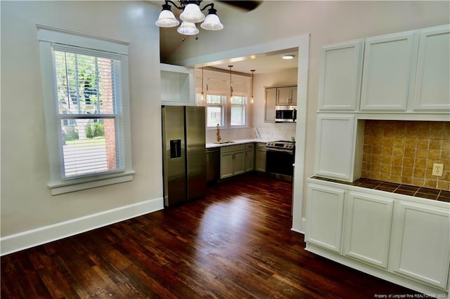 kitchen with a healthy amount of sunlight, hanging light fixtures, dark hardwood / wood-style floors, and appliances with stainless steel finishes