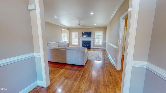 unfurnished living room with ceiling fan, wood-type flooring, and ornamental molding