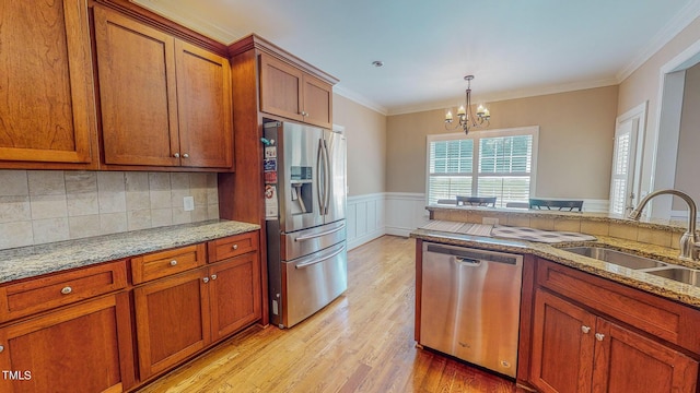 kitchen featuring ornamental molding, stainless steel appliances, sink, light hardwood / wood-style flooring, and a chandelier