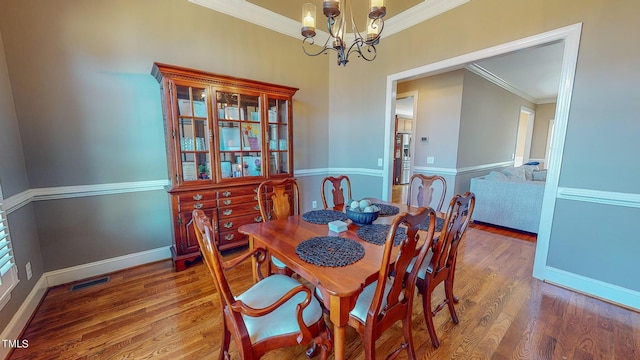 dining area with ornamental molding, a chandelier, and wood-type flooring