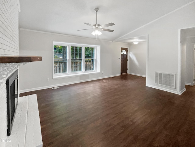 unfurnished living room featuring ceiling fan, dark hardwood / wood-style flooring, crown molding, vaulted ceiling, and a brick fireplace