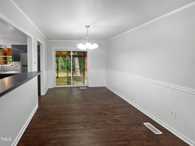 unfurnished dining area featuring an inviting chandelier, sink, dark hardwood / wood-style flooring, crown molding, and a textured ceiling