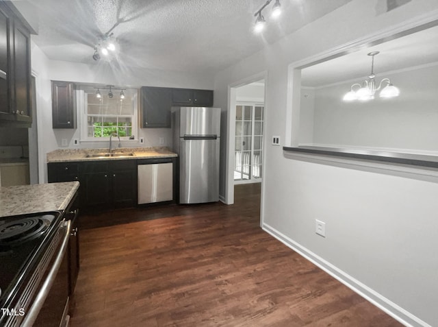 kitchen featuring sink, dark wood-type flooring, appliances with stainless steel finishes, a textured ceiling, and a chandelier