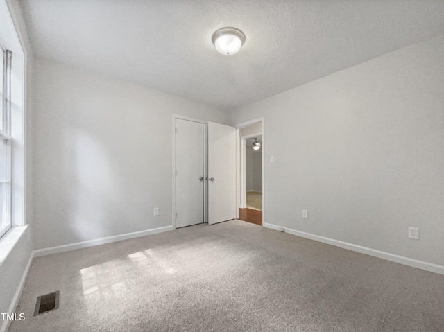 unfurnished room with a textured ceiling, a healthy amount of sunlight, and carpet