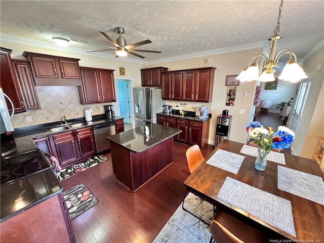 kitchen with tasteful backsplash, a kitchen island, a textured ceiling, and appliances with stainless steel finishes