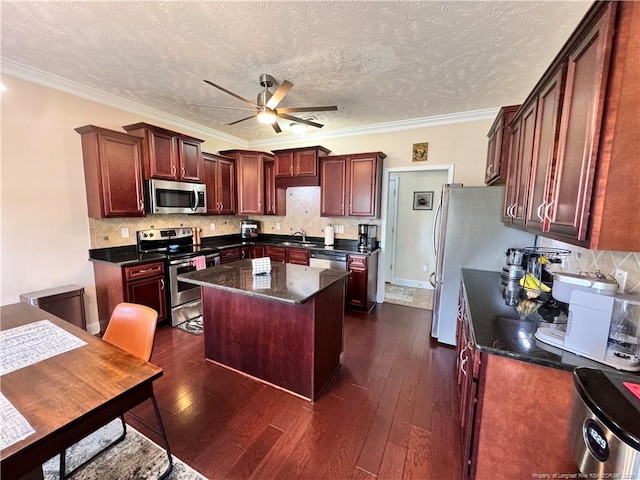 kitchen featuring sink, crown molding, appliances with stainless steel finishes, a center island, and a textured ceiling