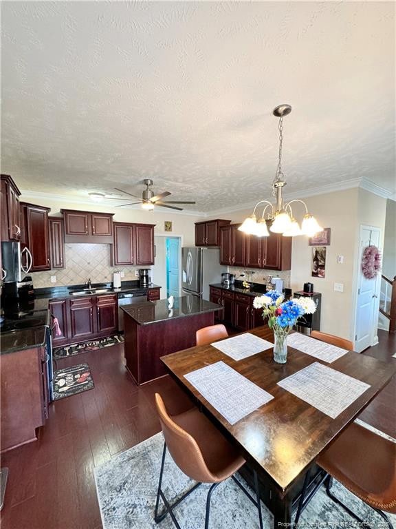 dining area featuring ceiling fan with notable chandelier, sink, crown molding, dark wood-type flooring, and a textured ceiling