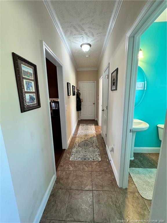 hall with ornamental molding, dark tile patterned flooring, and a textured ceiling