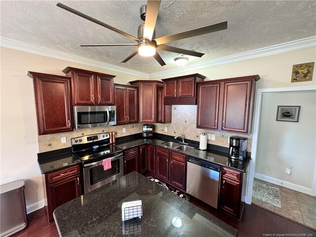 kitchen featuring sink, crown molding, tasteful backsplash, a textured ceiling, and stainless steel appliances