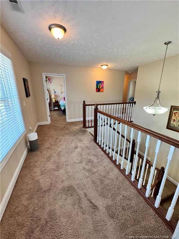 hallway featuring a textured ceiling and carpet flooring