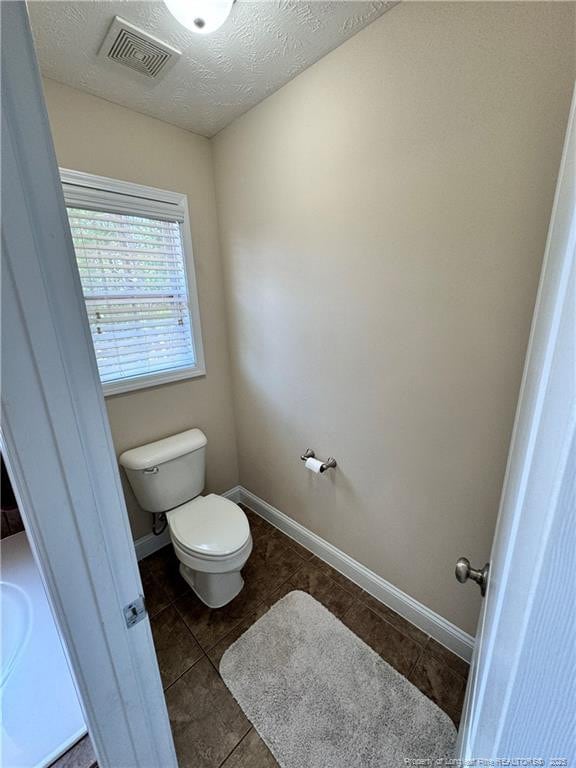 bathroom featuring tile patterned flooring, a textured ceiling, and toilet