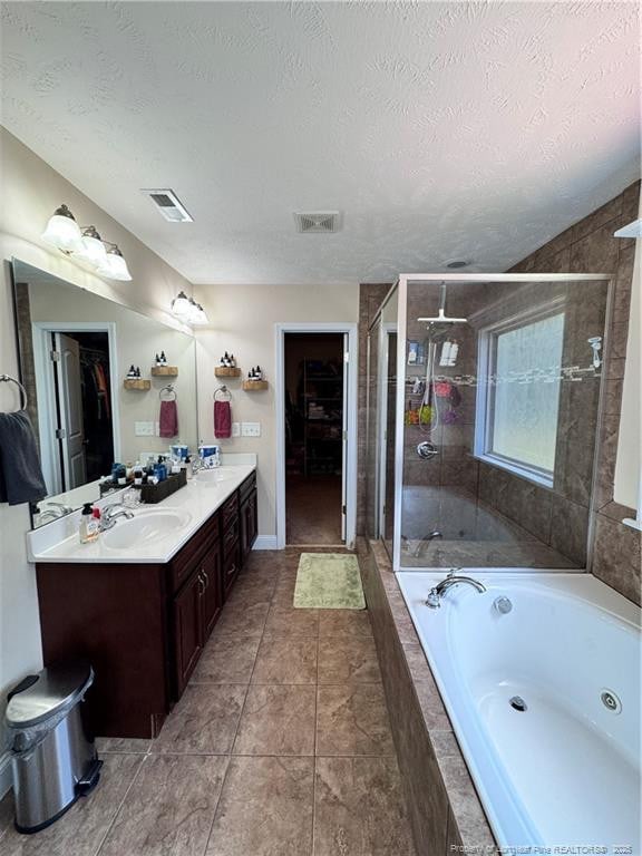 bathroom featuring vanity, tile patterned flooring, shower with separate bathtub, and a textured ceiling