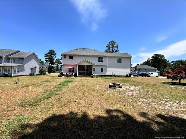 rear view of house with an outdoor fire pit and a yard