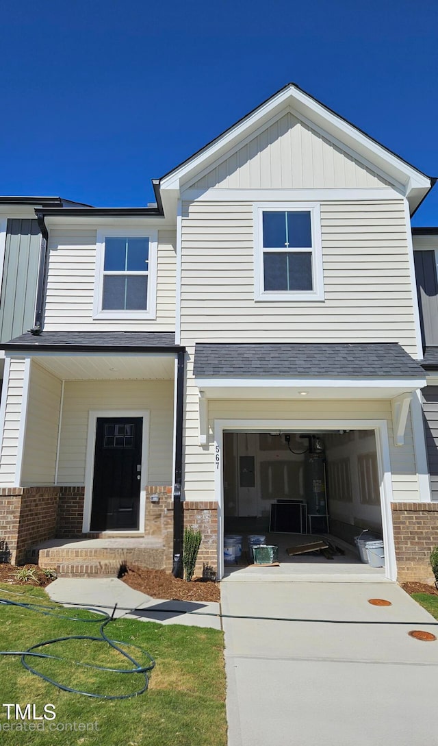 view of front of property with a garage, water heater, and a front lawn