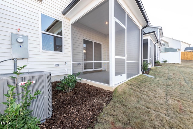 view of home's exterior with a lawn, a sunroom, and central air condition unit