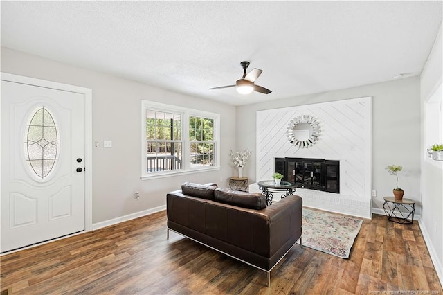 living room featuring plenty of natural light, ceiling fan, dark hardwood / wood-style flooring, and a brick fireplace