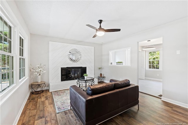 living room with ceiling fan, dark hardwood / wood-style floors, and a brick fireplace