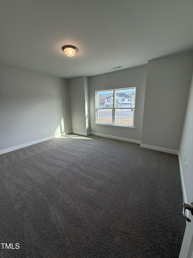 unfurnished room with dark carpet and baseboards