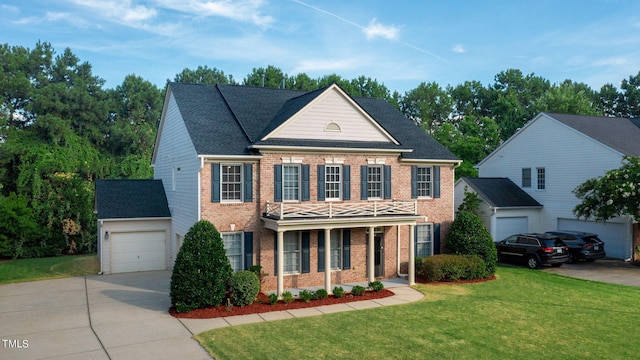 colonial inspired home featuring a garage and a front lawn