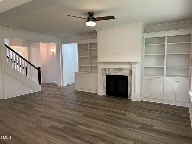 unfurnished living room featuring dark hardwood / wood-style floors, a fireplace, built in features, and crown molding