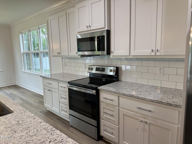 kitchen with light stone counters, decorative backsplash, white cabinets, and appliances with stainless steel finishes