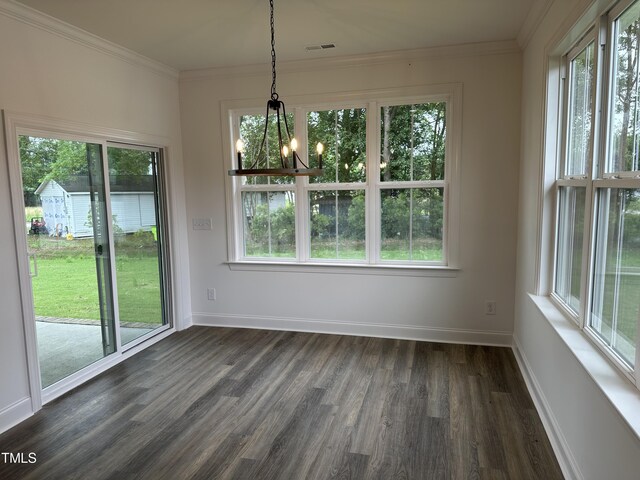 unfurnished dining area featuring ornamental molding, plenty of natural light, dark hardwood / wood-style floors, and a notable chandelier