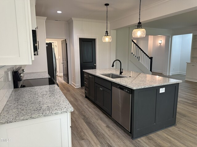 kitchen with stainless steel appliances, a kitchen island with sink, white cabinets, and decorative light fixtures