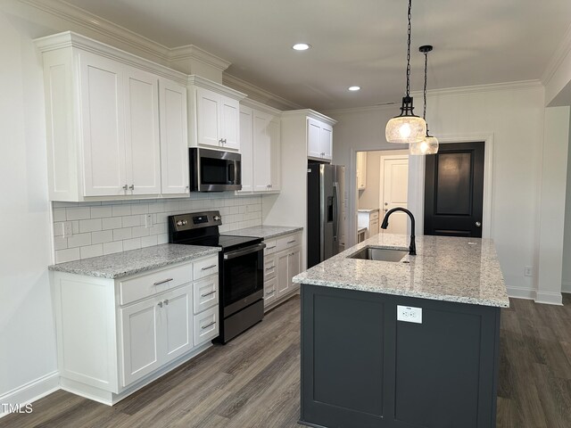 kitchen with appliances with stainless steel finishes, pendant lighting, sink, white cabinets, and a center island with sink