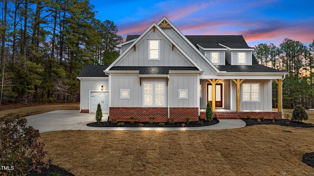 view of front of house with a porch, a garage, and a lawn