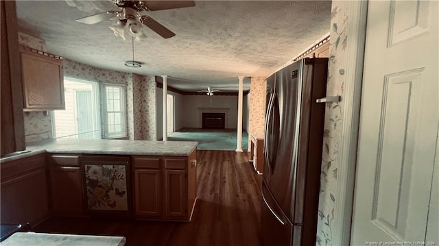 kitchen with dark hardwood / wood-style flooring, stainless steel refrigerator, a textured ceiling, ceiling fan, and kitchen peninsula