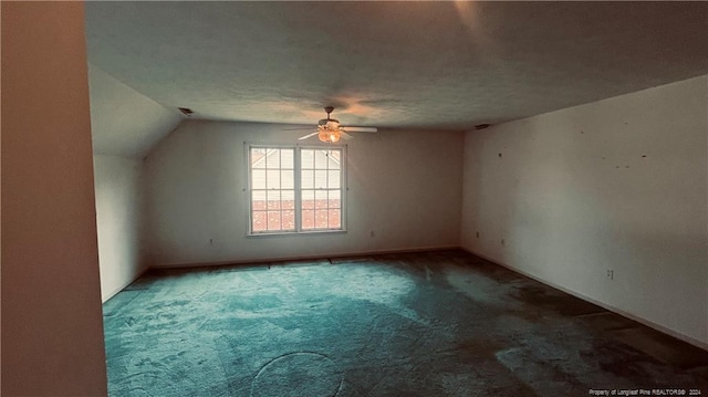 interior space with ceiling fan, carpet flooring, a textured ceiling, and lofted ceiling