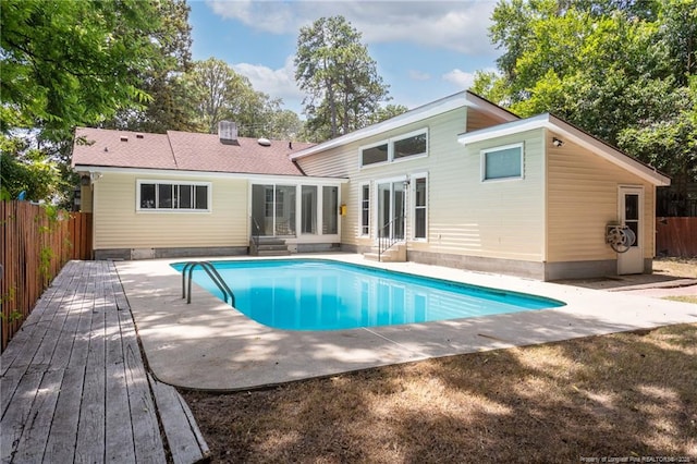 back of house with entry steps, a sunroom, a fenced backyard, and a fenced in pool