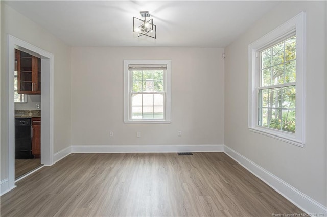 unfurnished room featuring visible vents, light wood-style flooring, and baseboards