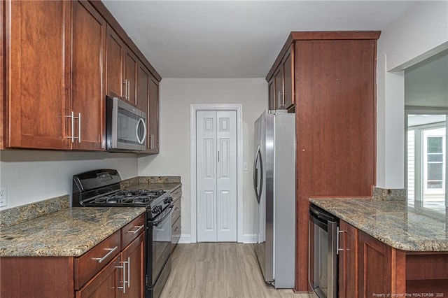 kitchen featuring beverage cooler, baseboards, dark stone countertops, stainless steel appliances, and light wood-style floors