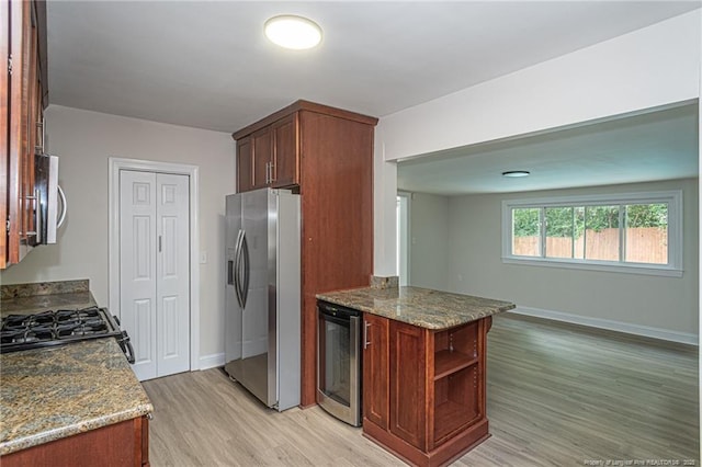 kitchen with beverage cooler, stainless steel appliances, baseboards, light wood-type flooring, and dark stone counters