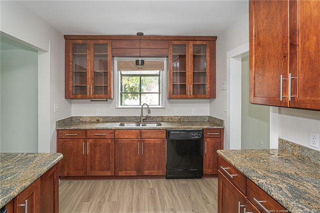 kitchen featuring black dishwasher, dark stone countertops, light wood-style flooring, and a sink