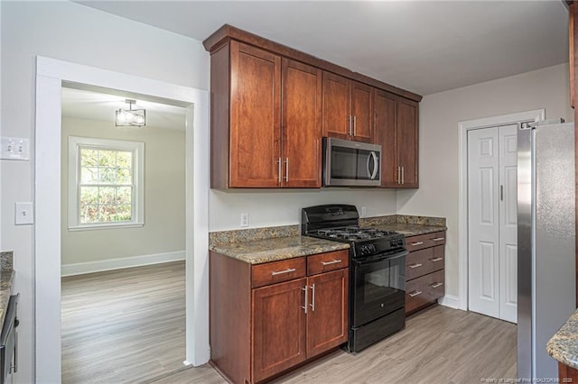 kitchen featuring stone counters, light wood-style flooring, baseboards, and stainless steel appliances