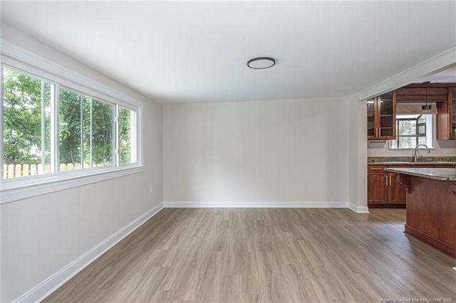 interior space with a sink, light wood-style flooring, and baseboards