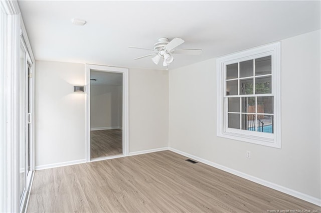 unfurnished room featuring light wood finished floors, baseboards, visible vents, and a ceiling fan