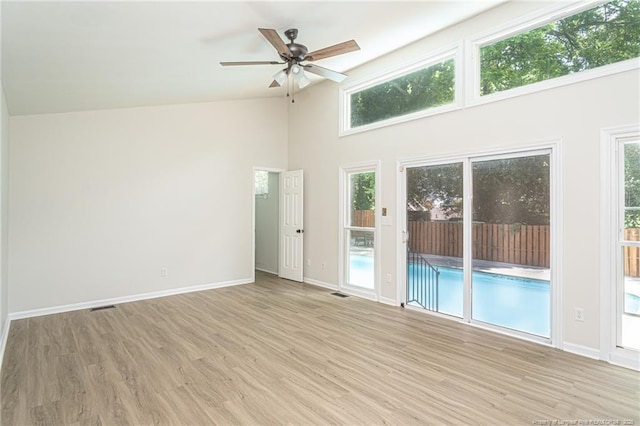 unfurnished room with ceiling fan, visible vents, light wood-style flooring, and baseboards