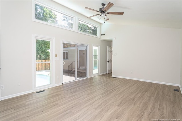 empty room with visible vents, light wood-style flooring, ceiling fan, high vaulted ceiling, and baseboards