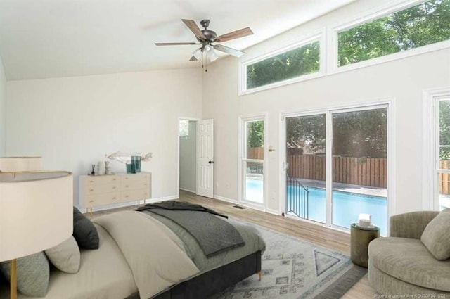 bedroom with access to exterior, visible vents, high vaulted ceiling, and wood finished floors