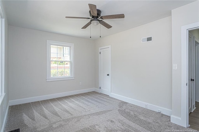 unfurnished room with carpet, visible vents, ceiling fan, and baseboards