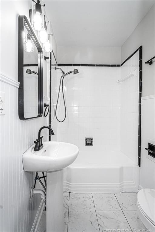 full bathroom with toilet, marble finish floor, and shower / tub combination