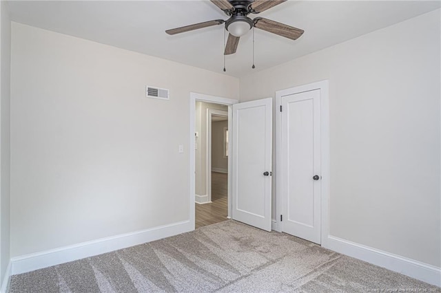 spare room featuring carpet, visible vents, ceiling fan, and baseboards