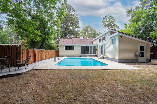 rear view of property with a yard, a patio area, fence, and a fenced in pool