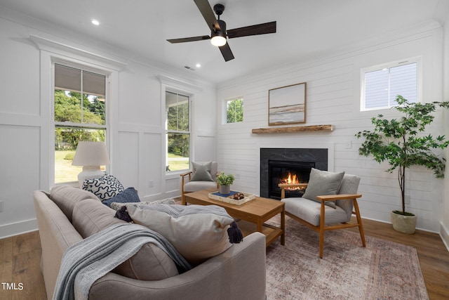 living room featuring dark wood-type flooring, ornamental molding, and ceiling fan