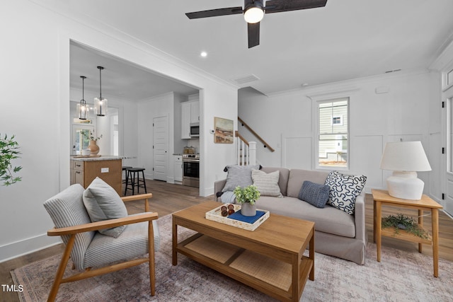 living room featuring ornamental molding, ceiling fan, and light hardwood / wood-style floors